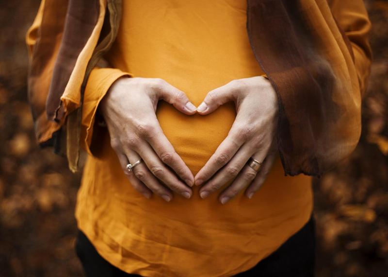 Pregnant woman making a heart shape with her hands on her belly
